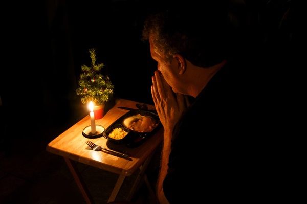 Man praying over a TV dinner at Christmas time